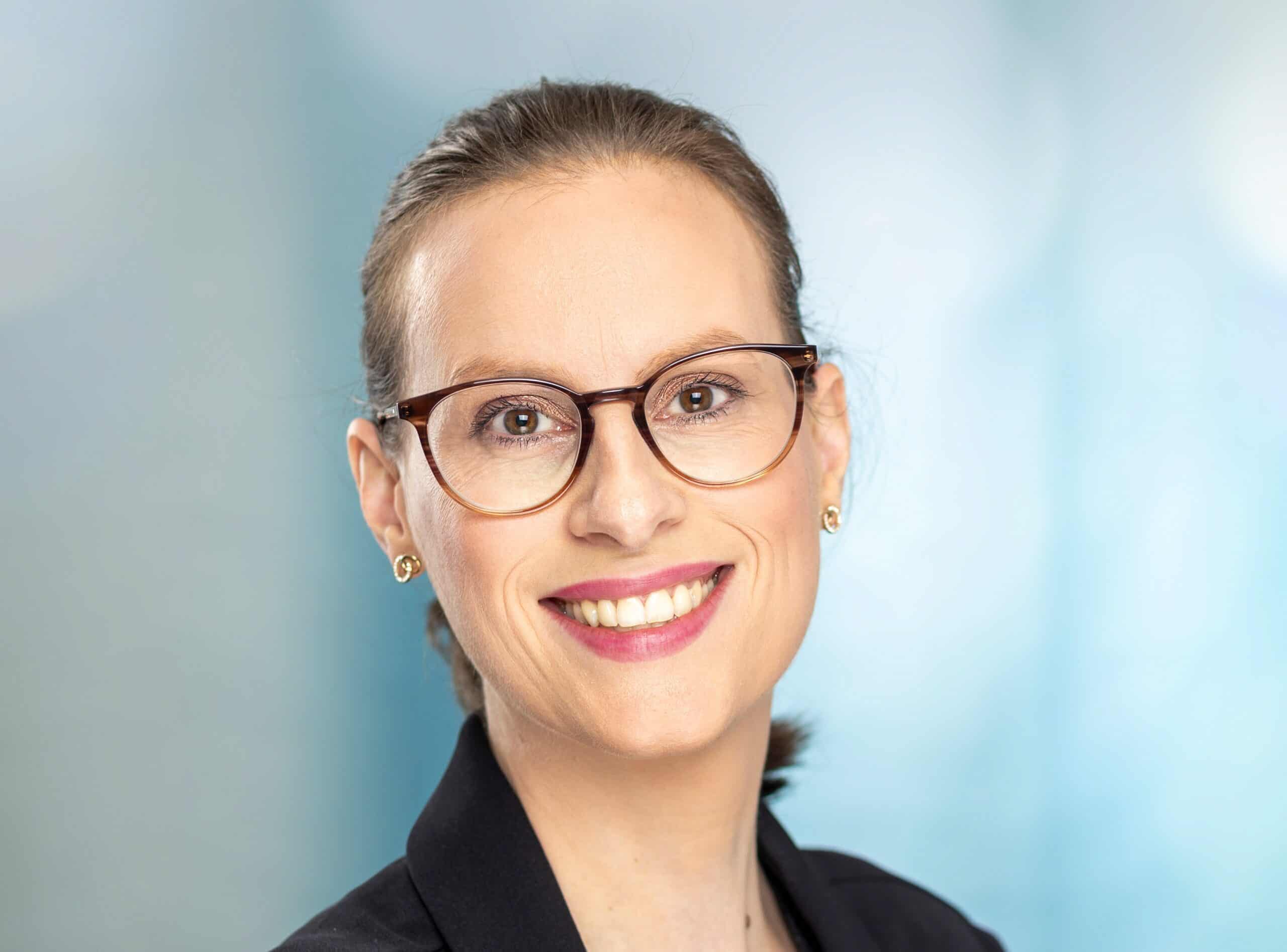 Frau mit Brille und schwarzem Blazer l&auml;chelt freundlich.